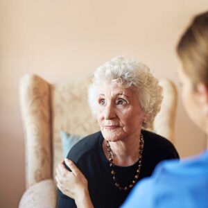 Older adult and family member reviewing care costs, benefit documents, and a calculator at a kitchen table.